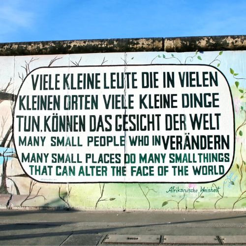 Wand mit Graffiti Aufschrift "Viele kleine Leute die in vielen kleinen Orten viele kleine Dinge tun, können das Gesicht der Welt verändern."