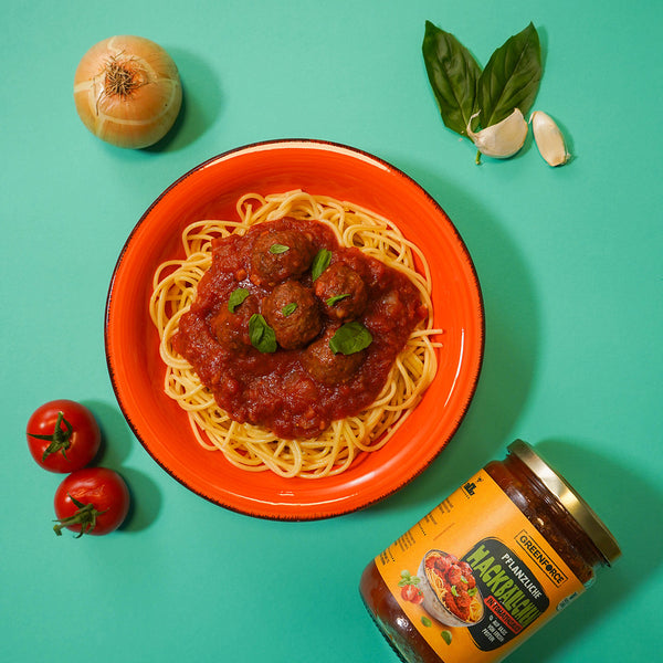 Leckere pflanzliche Hackbällchen in Tomatensauce angerichtet auf Spaghetti mit Basilikum on top